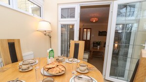A dining area with a round table set for breakfast, including croissants, coffee, and juice. - Maple Cottage (Broadway)