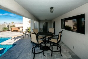 Um alpendre coberto com piscina, área de estar externa e vista para a paisagem.
