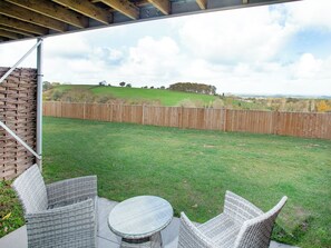 A patio with wicker furniture and a view of a grassy yard enclosed by a wooden fence. - 2 bedroom accommodation in Over Stowey, near Bridgwater (Over Stowey, near Bridgwater)