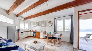A spacious living area with a kitchen, dining table, and a view of the sea. - Le Pescadou - Terrasse vue mer (Marseille)