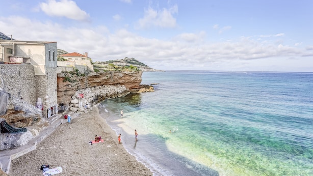 A coastal beach with clear waters, a rocky cliff, and a few people enjoying the area. - Le Pescadou - Terrasse vue mer (Marseille)