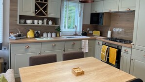 A modern kitchen with copper pendant lights, a built-in microwave, and a gas stove. - Luxurious and Cosy Holiday Lodge in the New Forest National Park (Landford)