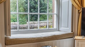 Ein Zimmer mit Fensterbank, einem Korbwäscheschrank mit Handtüchern und einem Fernseher auf einem Holzboden.