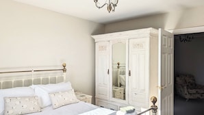 A bedroom with a bed, a wardrobe, and a chair. - 4 bedroom accommodation in Winscales (Winscales)