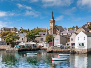 Une ville côtière dotée d’un clocher d’église imposant, d’eaux calmes et de petits bateaux.
