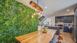 A modern kitchen with a wooden dining table, a green vertical garden wall, and stainless steel appliances. - Private Pool- Hot Tub- Playground- Fire Pit- Fenced In Backyard- Pets! (Pocono Mountains)