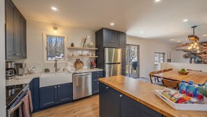 A modern kitchen with dark cabinets, stainless steel appliances, and a wooden island with snacks. - Private Pool- Hot Tub- Playground- Fire Pit- Fenced In Backyard- Pets! (Pocono Mountains)