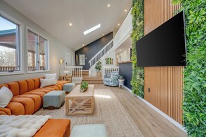 Un salon moderne avec un canapé d’angle, une table basse et un escalier menant à un niveau supérieur.