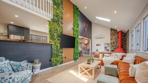 A modern living room with a sofa, a coffee table, a TV, and a fireplace. - Private Pool- Hot Tub- Playground- Fire Pit- Fenced In Backyard- Pets! (Pocono Mountains)