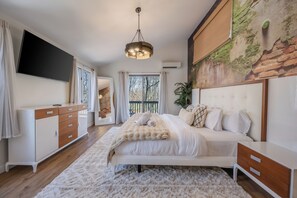 A bedroom with a bed, a dresser, a TV, a ceiling light, and a mural on the wall.