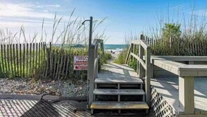 A wooden staircase leading to a beach area with a sign indicating 'STAIRS AM SHOW ADMIRAL QUARTER'.
