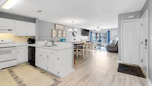 A modern kitchen with white cabinets, a central island, and a dining area with a table and chairs.