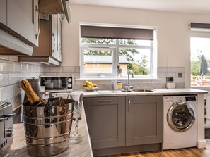 Una cocina moderna con lavadora integrada, microondas y un amplio ventanal.