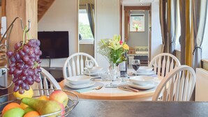 A dining table set with plates, glasses, and a bowl of fruit.