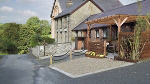 A stone building with a wooden porch and a gravel driveway.