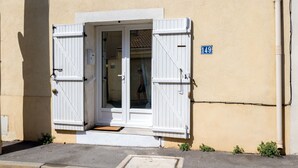 A building entrance with a white door and shutters, a small step leading up to it, and a blue sign with the number 149.