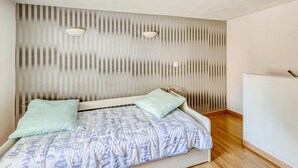 A modern bedroom with a bed, two pillows, a striped wall, and a white ceiling.