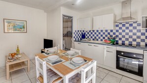 A modern kitchen with white cabinets, a checkered backsplash, and a dining area set for four.