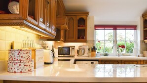 Una cocina con armarios de madera, microondas, tostadora y ventana con vistas a la vegetación.