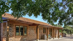 A stone building with a tiled roof, large windows, and a covered outdoor area.