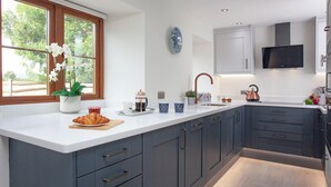A modern kitchen with a large island, dark cabinets, and a window with flowers.