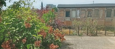 Un edificio con fachada de piedra, una cerca metálica y cielo despejado.