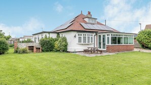 A house with a tiled roof, a covered patio, and a grassy yard. - 3 bedroom accommodation in Sandilands (Sandilands)