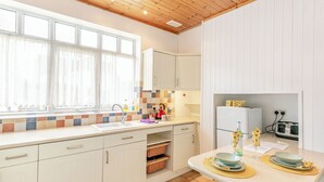 A modern kitchen with white cabinets, a tiled backsplash, and a wooden ceiling. - 3 bedroom accommodation in Sandilands (Sandilands)