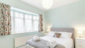A bedroom with a bed, a nightstand, a lamp, a radiator, and curtains. - 3 bedroom accommodation in Sandilands (Sandilands)