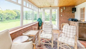 A sunlit room with large windows, wicker furniture, and a brick wall. - 3 bedroom accommodation in Sandilands (Sandilands)