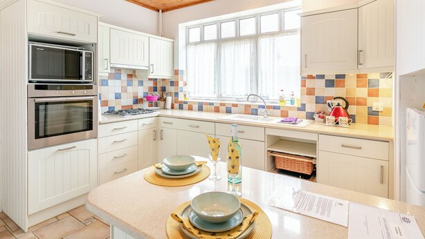 A modern kitchen with white cabinets, a microwave, oven, and a window with curtains. - 3 bedroom accommodation in Sandilands (Sandilands)