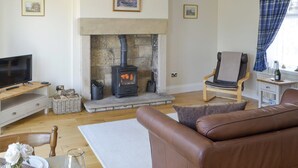 Un salon avec une cheminée en pierre, un téléviseur, un canapé en cuir et un fauteuil.