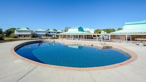 Ein großer, runder Pool mit einer Ziegelkante, umgeben von einer überdachten Terrasse mit weißem Zaun.