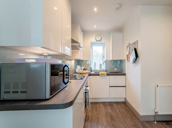 A modern kitchen with white cabinets, a built-in microwave, and a window with a view.