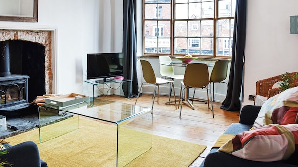 Un salon avec une cheminée, une table basse en verre, un téléviseur et un coin repas avec des chaises.