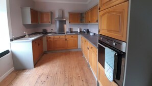Une cuisine avec des armoires en bois, une hotte de cuisinière en acier inoxydable et un four encastré.