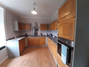 Una cocina con gabinetes de madera, una campana extractora de acero inoxidable y un horno empotrado.
