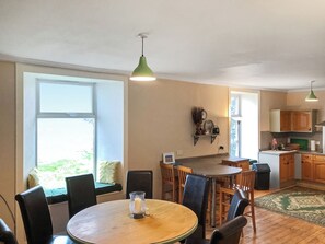 A dining area with a wooden table, chairs, a vase, and a window with a view.
