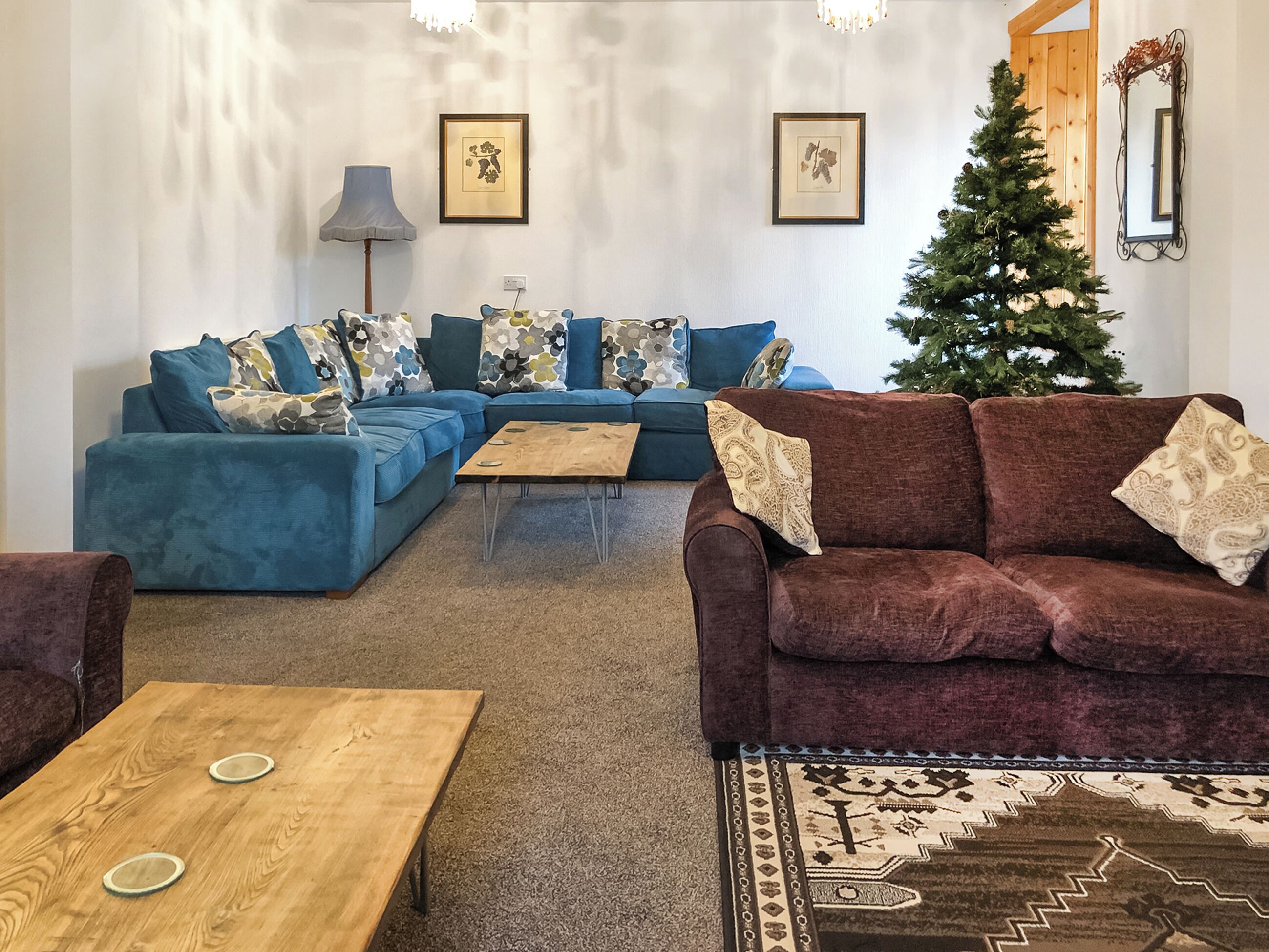 Una sala de estar con un sofá seccional, una mesa de centro y un árbol de Navidad.