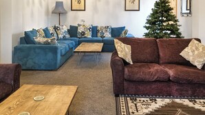 Un salon avec un canapé d’angle, une table basse et un sapin de Noël.