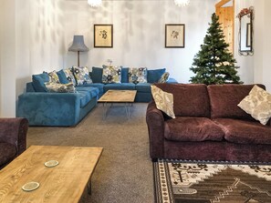 Una sala de estar con un sofá seccional, una mesa de centro y un árbol de Navidad.
