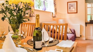 Une table à manger avec une bouteille de champagne, des verres et un vase rempli de fleurs jaunes.