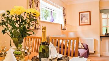 A dining table with a bottle of champagne, glasses, and a vase of yellow flowers.