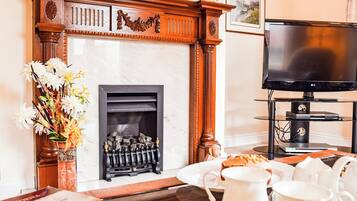 A living room with a fireplace, a television, and a dining area with a table set for breakfast.