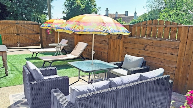 A patio area with wicker furniture, a table, and colorful umbrellas.