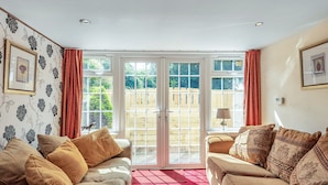 A cozy living room with two sofas, a red rug, and a large sliding glass door leading to a wooden deck.