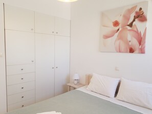 Ein Schlafzimmer mit Bett, Nachttisch, Kleiderschrank und einem an der Wand hängenden Gemälde.