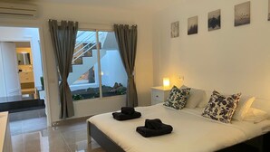 Um quarto moderno com uma cama grande, uma mesa de cabeceira e uma janela com cortinas.