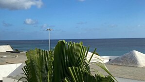Terraço no telhado com vista para o oceano, com um poste de luz e estruturas brancas.