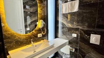 A modern bathroom with a marble vanity, a toilet, and a towel rack.